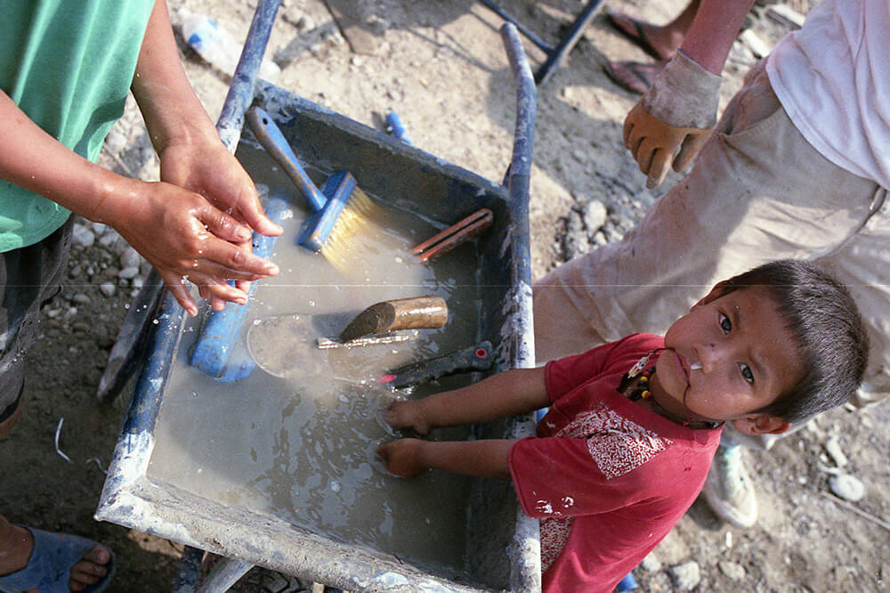 Nepalese kids wahsing his hand in a wheel barrow